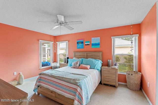 bedroom featuring a textured ceiling, ceiling fan, and light carpet