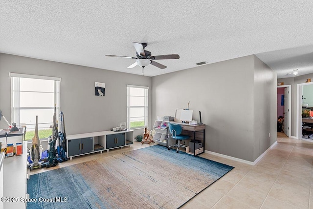 misc room featuring ceiling fan, light tile patterned flooring, and a textured ceiling