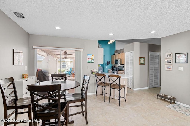 tiled dining space with a textured ceiling and ceiling fan