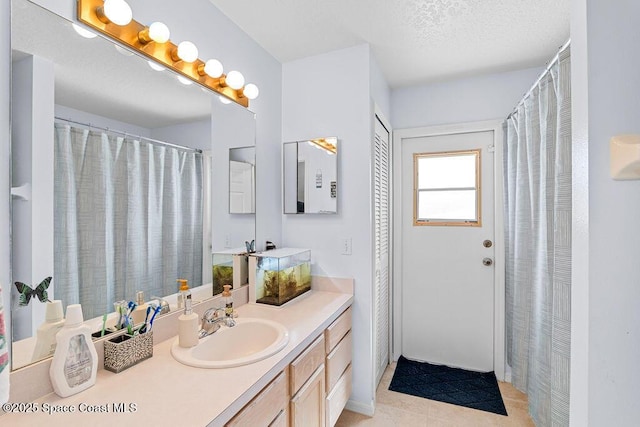 bathroom with tile patterned flooring, vanity, and a textured ceiling