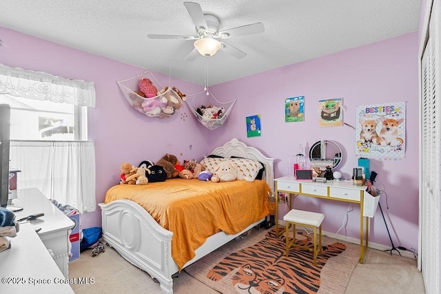 bedroom with a textured ceiling, light colored carpet, and ceiling fan