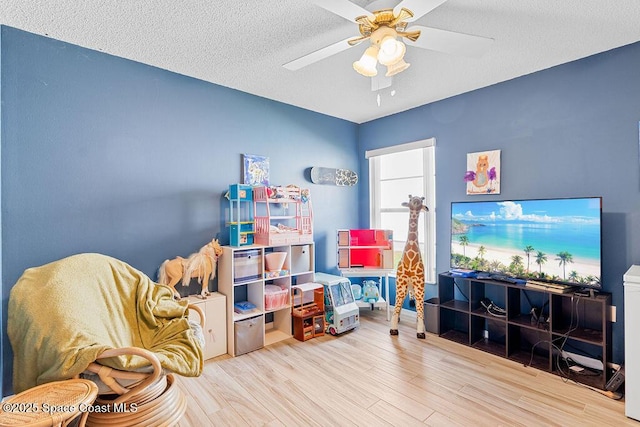 game room featuring ceiling fan, hardwood / wood-style floors, and a textured ceiling