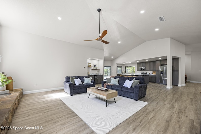 living room with light wood-type flooring, high vaulted ceiling, and ceiling fan