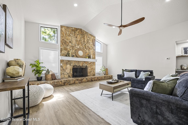 living room featuring ceiling fan, a fireplace, high vaulted ceiling, and wood-type flooring