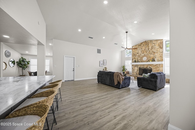 living room with a fireplace, wood-type flooring, lofted ceiling, and a healthy amount of sunlight