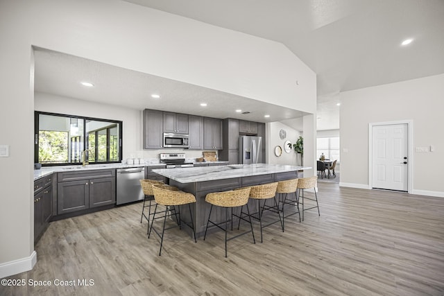 kitchen with a kitchen bar, vaulted ceiling, stainless steel appliances, and a kitchen island