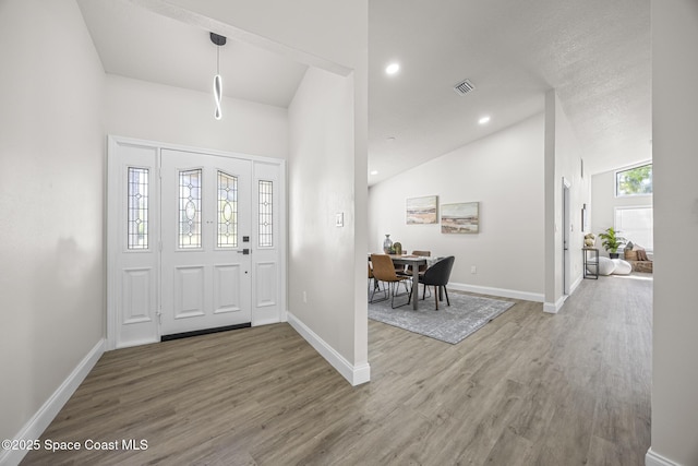 foyer entrance featuring hardwood / wood-style flooring and high vaulted ceiling