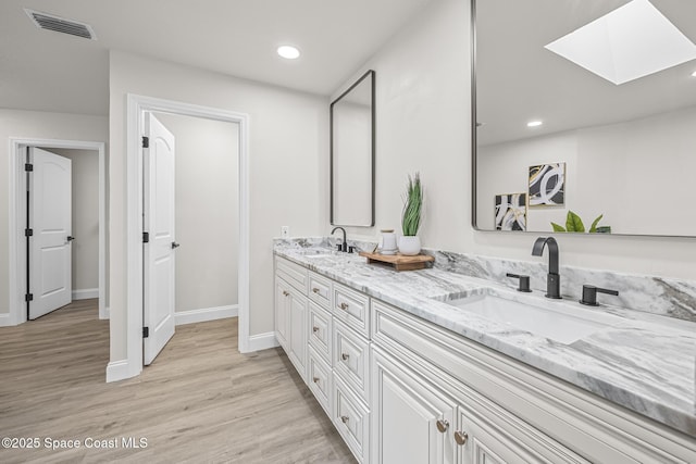 bathroom with vanity, a skylight, and hardwood / wood-style flooring