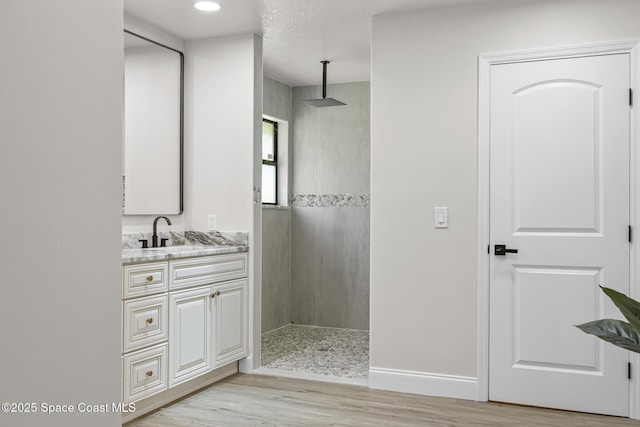 bathroom featuring hardwood / wood-style floors, vanity, and walk in shower