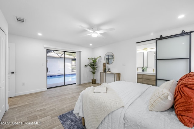 bedroom with access to outside, light hardwood / wood-style flooring, ceiling fan, a barn door, and connected bathroom