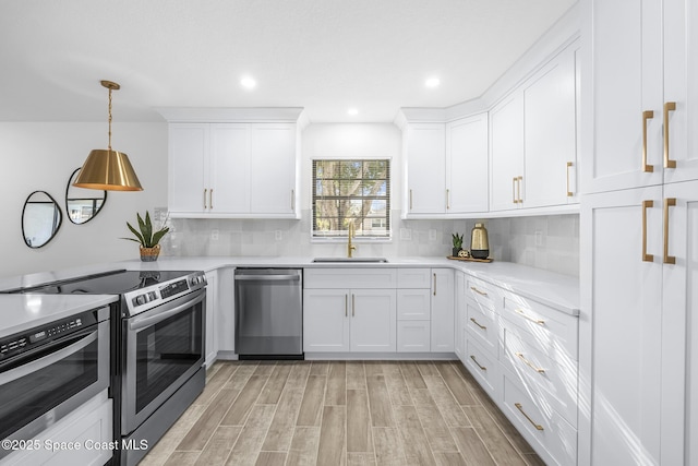 kitchen featuring decorative light fixtures, sink, white cabinetry, and stainless steel appliances