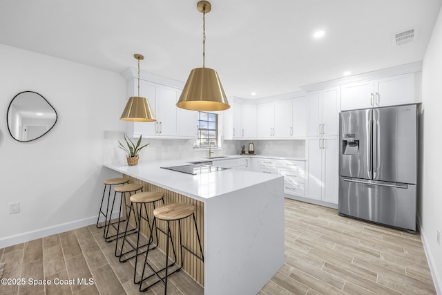 kitchen with backsplash, white cabinets, sink, stainless steel refrigerator with ice dispenser, and kitchen peninsula