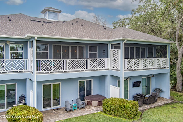 rear view of property featuring a jacuzzi, ceiling fan, a balcony, and a patio