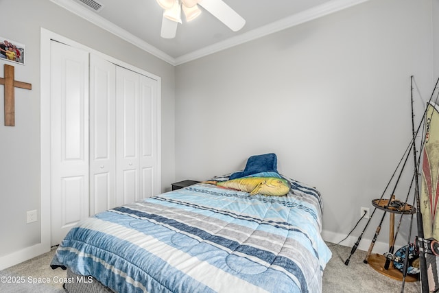 carpeted bedroom with ceiling fan, a closet, and crown molding