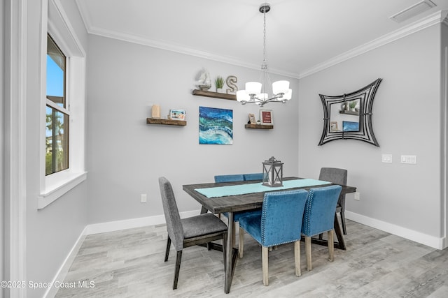 dining room with a notable chandelier, light hardwood / wood-style floors, and crown molding