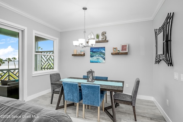 dining space featuring crown molding, light hardwood / wood-style flooring, and an inviting chandelier