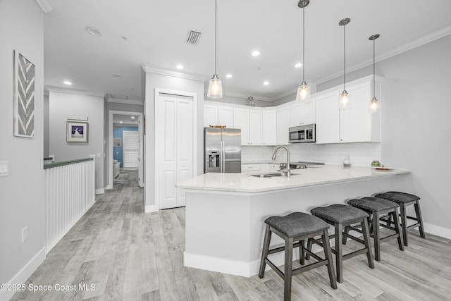 kitchen featuring kitchen peninsula, appliances with stainless steel finishes, sink, pendant lighting, and white cabinets