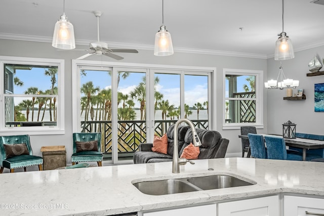 kitchen with white cabinets, pendant lighting, light stone counters, and sink