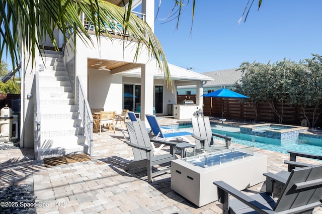 view of patio with an outdoor fire pit, area for grilling, and a pool with hot tub