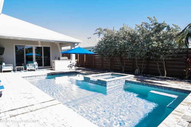 view of swimming pool with an in ground hot tub, a patio, and an outdoor kitchen