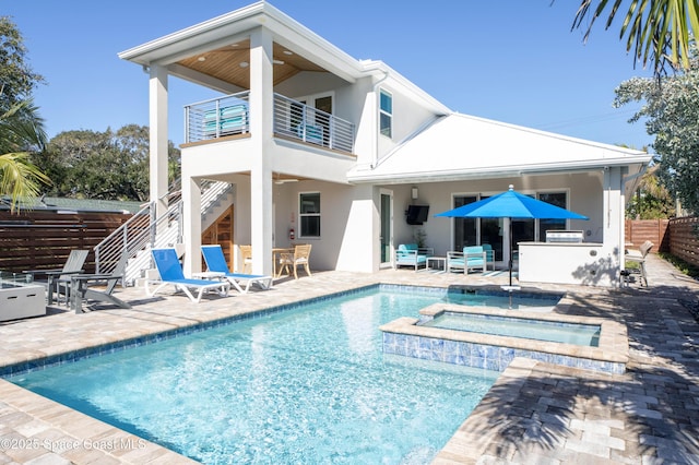 rear view of property with a pool with hot tub, a balcony, an outdoor bar, and a patio