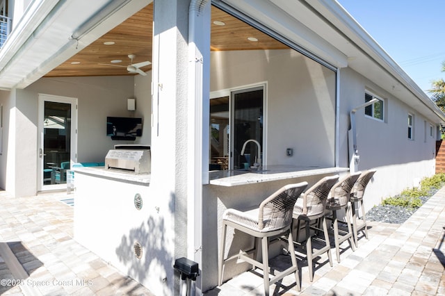 view of patio with ceiling fan and an outdoor wet bar