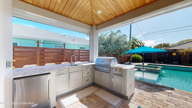 view of patio / terrace with a swimming pool with hot tub, area for grilling, and sink