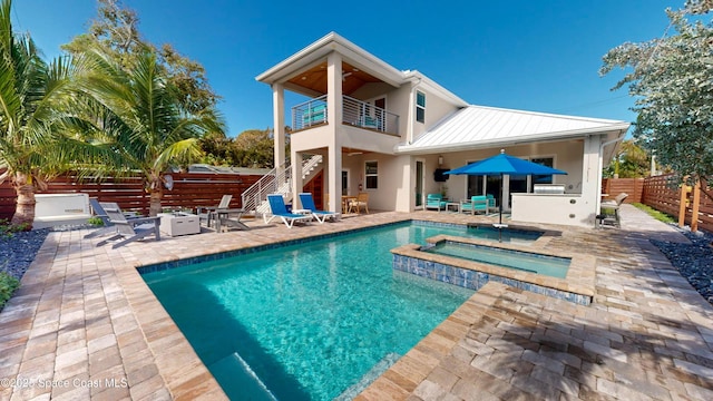 back of property featuring a swimming pool with hot tub, a balcony, and a patio area