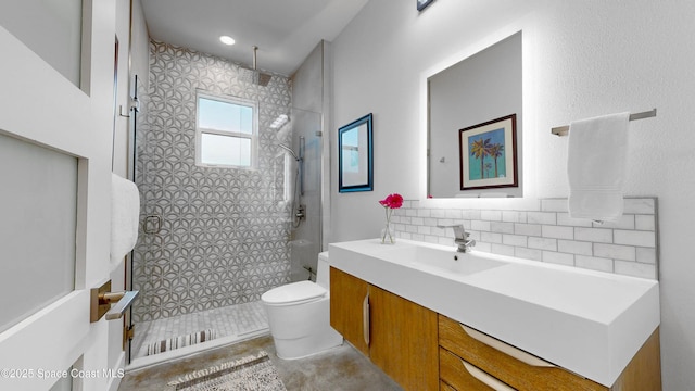 bathroom featuring vanity, backsplash, tiled shower, and toilet