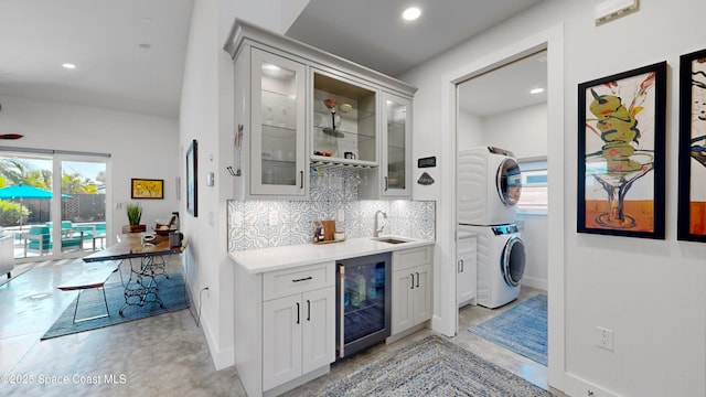 interior space featuring stacked washer / dryer, decorative backsplash, sink, and wine cooler