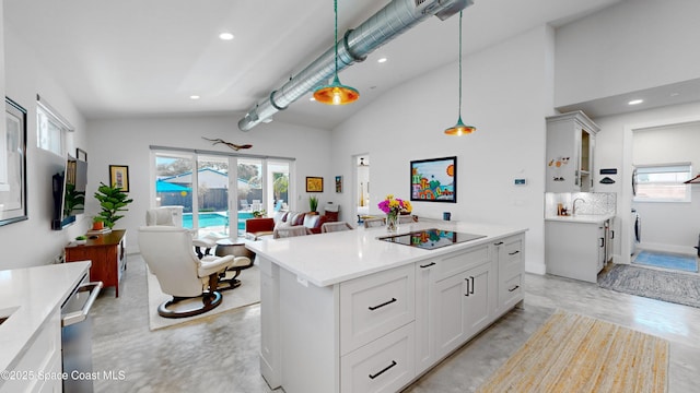 kitchen with black electric stovetop, vaulted ceiling, decorative light fixtures, and white cabinetry