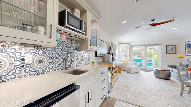 kitchen featuring backsplash, white cabinets, sink, ceiling fan, and stainless steel appliances