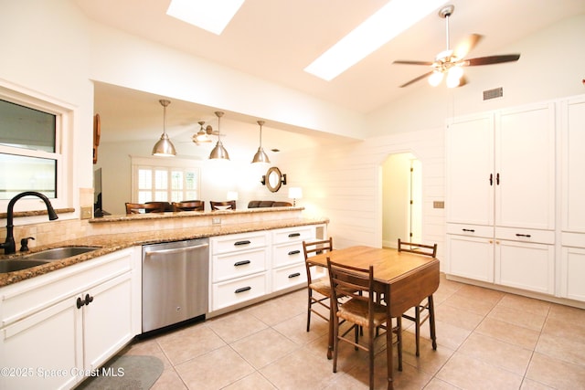 kitchen with sink, hanging light fixtures, stainless steel dishwasher, vaulted ceiling with skylight, and white cabinets