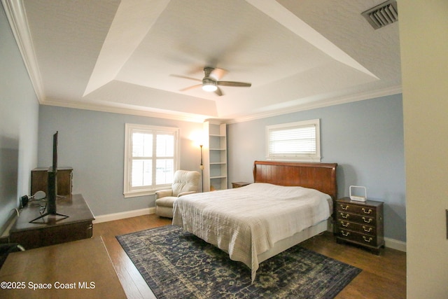 bedroom with ceiling fan, dark hardwood / wood-style floors, a raised ceiling, and multiple windows