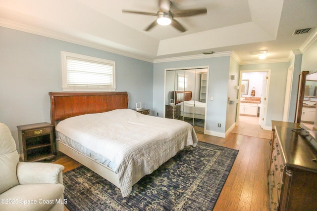 bedroom featuring a tray ceiling, ceiling fan, a closet, and light hardwood / wood-style floors