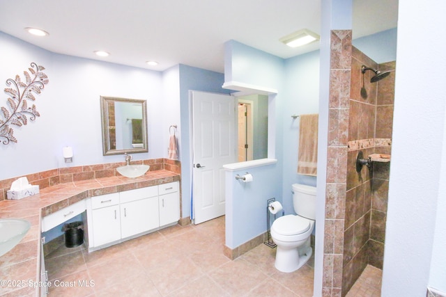 bathroom with tiled shower, vanity, toilet, and tile patterned flooring