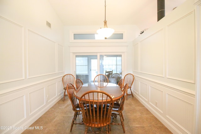 tiled dining room featuring high vaulted ceiling