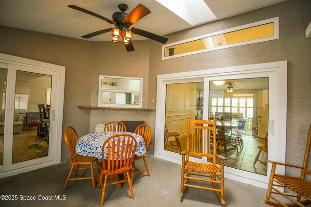 dining space featuring concrete floors, a skylight, and ceiling fan