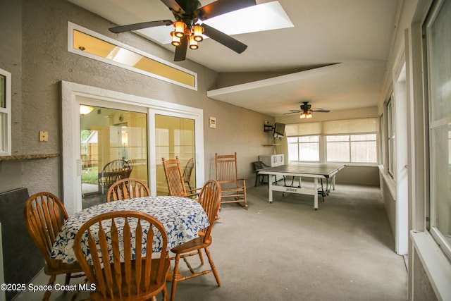 dining area featuring vaulted ceiling with skylight, ceiling fan, and concrete flooring