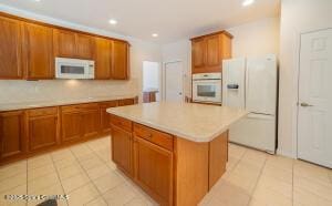 kitchen featuring white appliances, a center island, and light tile patterned flooring