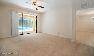 carpeted spare room featuring ceiling fan with notable chandelier