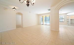 spare room featuring light tile patterned flooring and an inviting chandelier