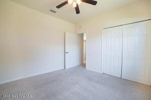 unfurnished bedroom with ceiling fan, carpet, and a closet