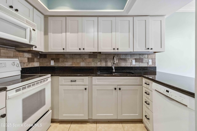 kitchen featuring white cabinetry, sink, dark stone countertops, white appliances, and light tile patterned floors