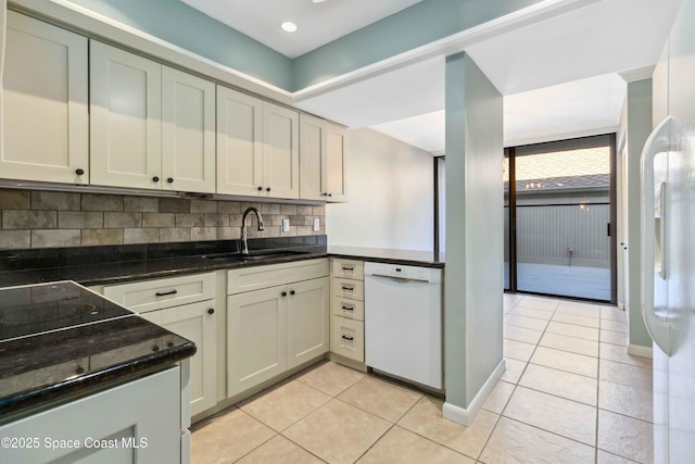 kitchen with white appliances, backsplash, sink, dark stone countertops, and light tile patterned floors