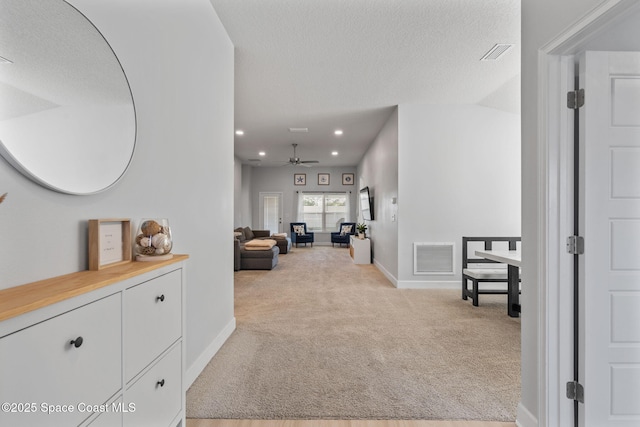 corridor featuring vaulted ceiling, light colored carpet, and a textured ceiling