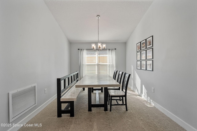 dining room featuring carpet, a textured ceiling, and a notable chandelier