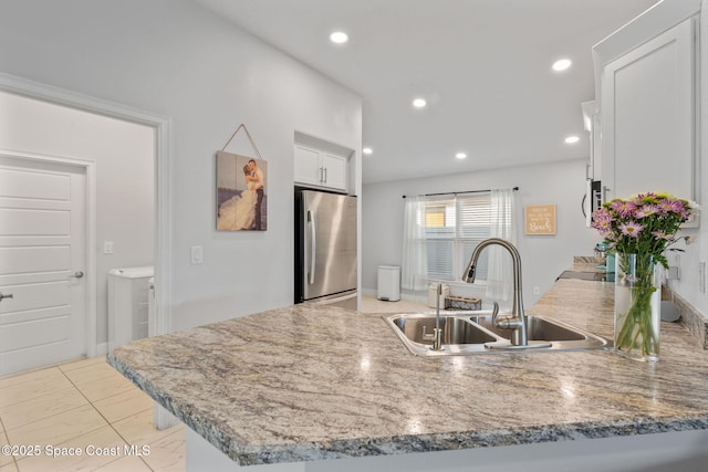 kitchen with sink, white cabinetry, stainless steel fridge, light tile patterned flooring, and kitchen peninsula