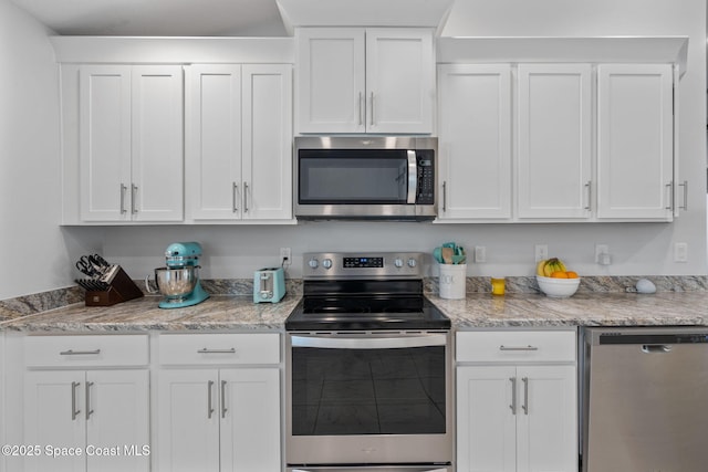 kitchen with light stone countertops, white cabinets, and stainless steel appliances