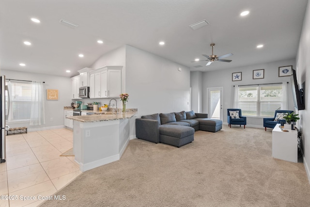 carpeted living room featuring ceiling fan and sink